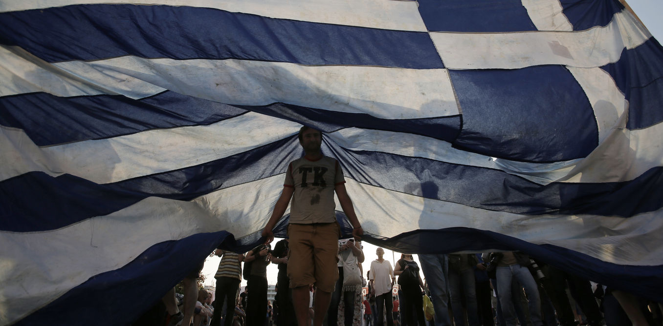 Protesters hold a giant a Greek flag during a rally in Athens, Greece, 29 June 2015. Greek voters will decide in a referendum on 05 July whether their government should accept an economic reform package put forth by Greece's international creditors. Greece has imposed capital controls and the banks will be closed until the referendum is held. EPA/YANNIS KOLESIDIS
