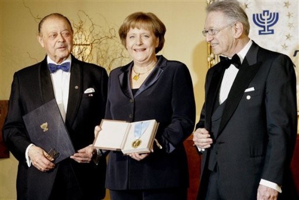 German Chancellor Angela Merkel, center, smiles as she is awarded with the "B'nai B'rith Europe Award of Merit" in the German capital Berlin Tuesday, March 11, 2008. Jewish organization B'nai B'rith honored Merkel for her engagement in fighting anti-semitism and racism. At left stands B'nai B'rith President Reinold Simon, and at right, Honorary President Joseph Domberger. (AP Photo/Fritz Reiss)